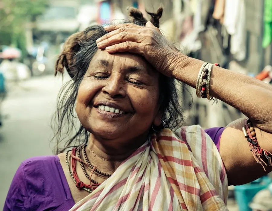 A smiling older woman with her hand on her forehead