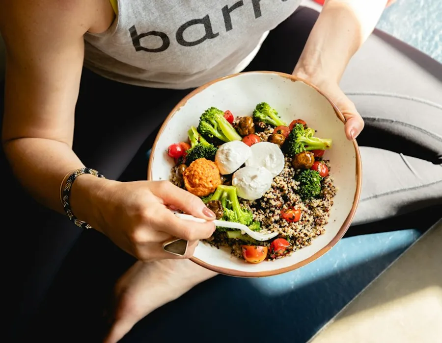 A person holding a bowl of vegetables and grains